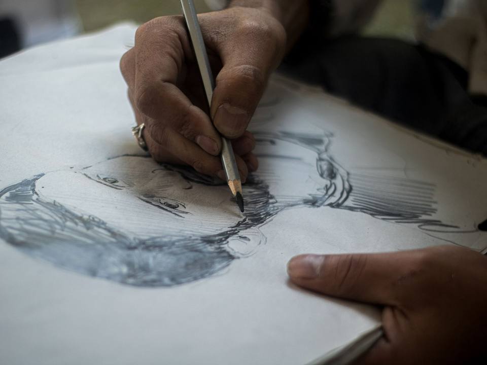 Hand drawing a pencil portrait sketch in a sketchbook