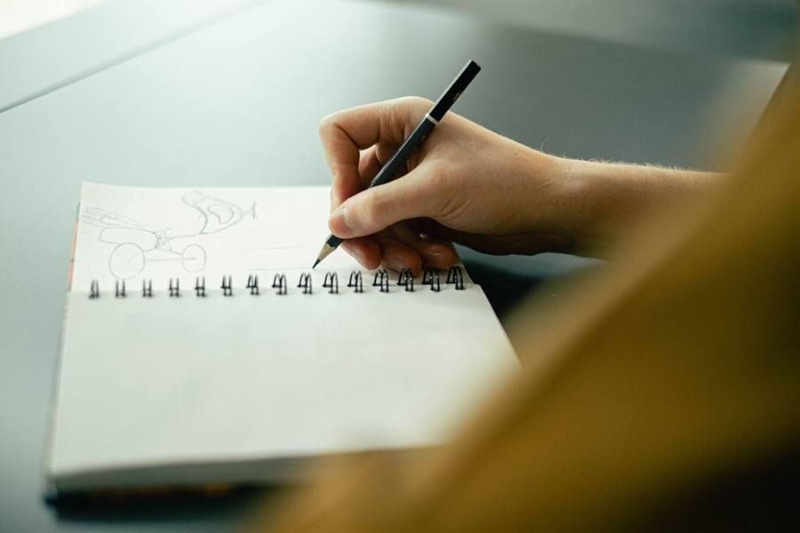 Hand sketching simple pencil drawings in a spiral-bound sketchbook