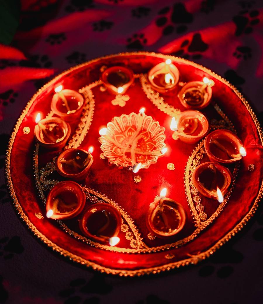 Decorated red thali with lit clay diyas arranged in a circle for Diwali