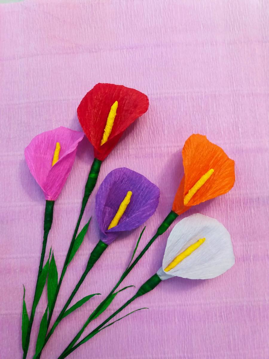 Handmade crepe-paper calla lilies in red, pink, purple, orange and white on a pink background