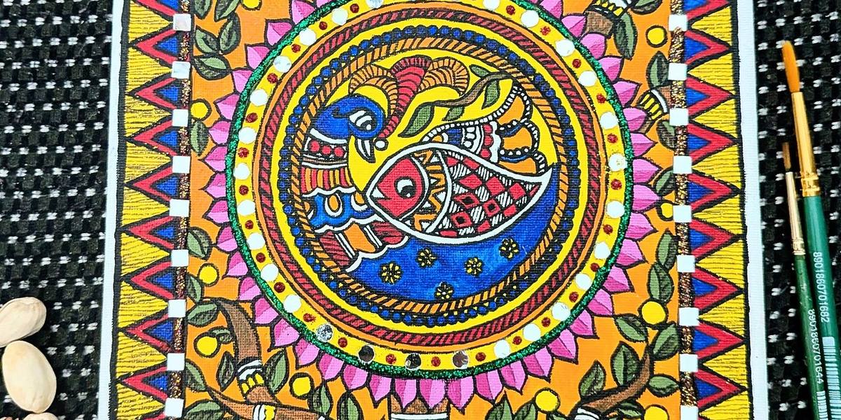 Madhubani painting of a peacock and fish in a circle, framed by leaves, lotus petals and triangle borders, with brushes beside it