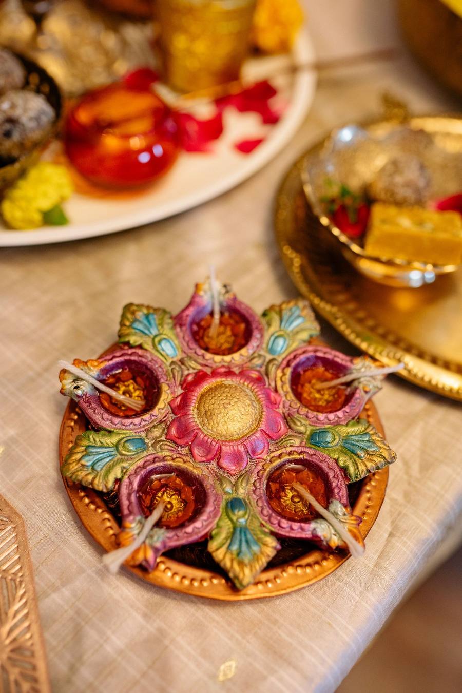 Hand-painted flower-shaped diya in pink, green and gold on a festive table